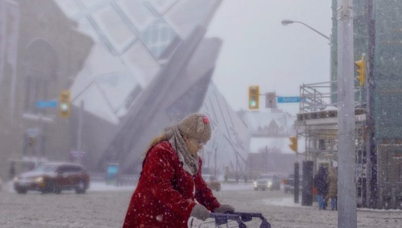 senior woman using walker for moving alone through snowy pathway