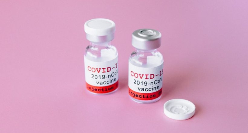 two covid vials on pink surface