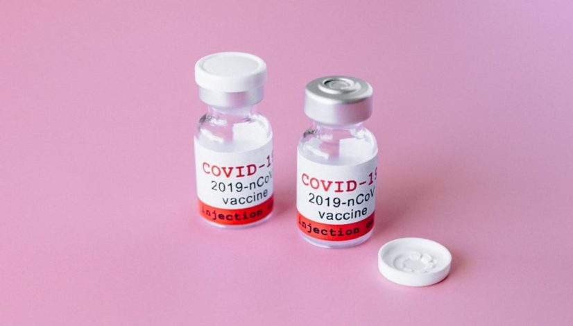 two covid vials on pink surface