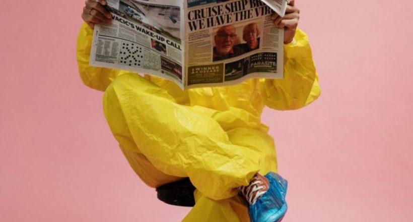 man in yellow protective suit holding a newspaper