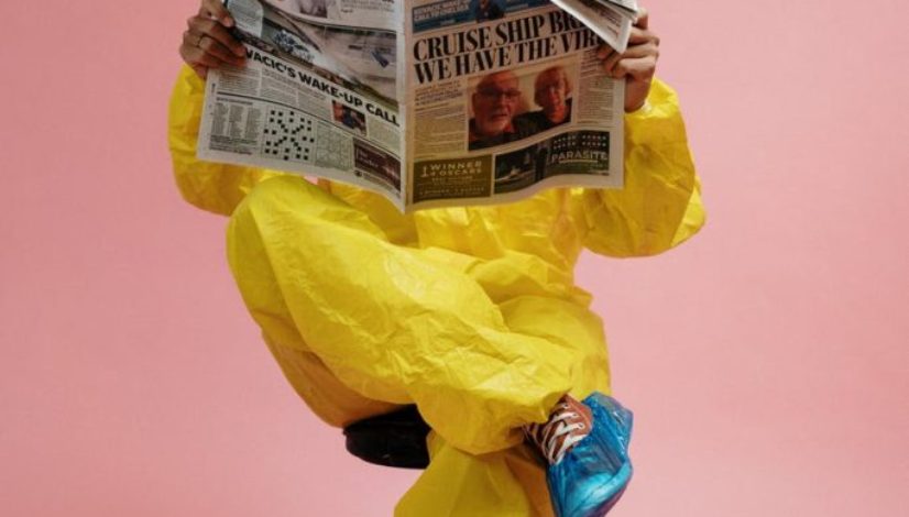 man in yellow protective suit holding a newspaper