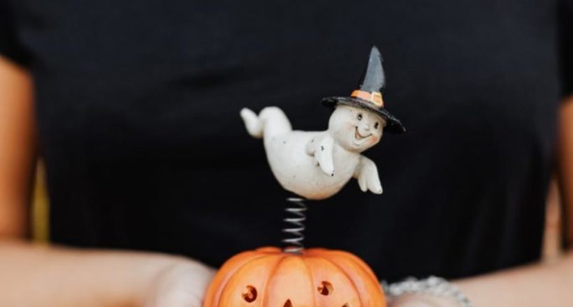 person holding a toy jack o lantern with a ghost