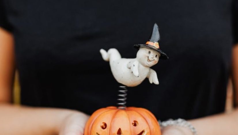 person holding a toy jack o lantern with a ghost